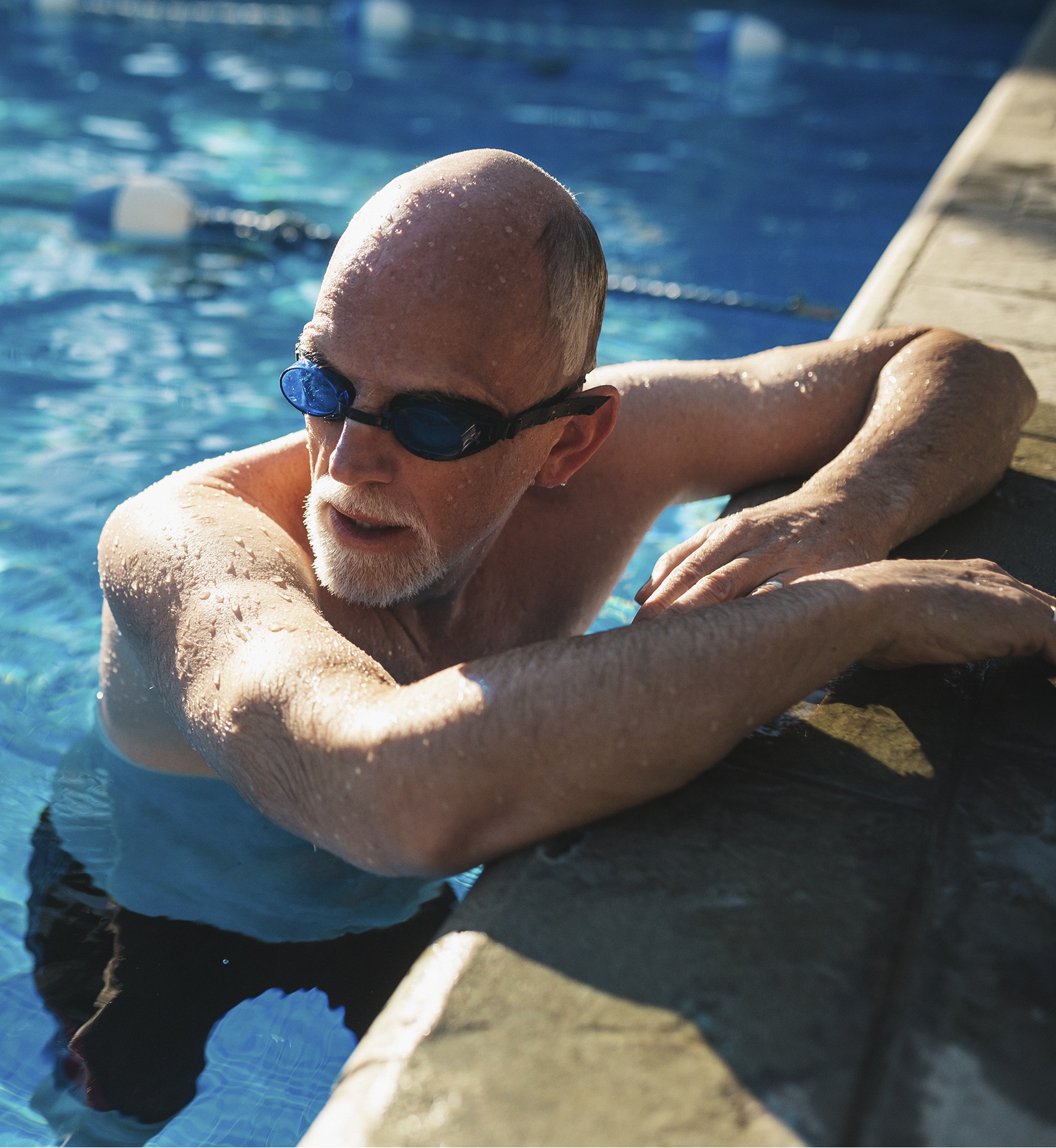 Active oler man working out at outdoor swimming pool